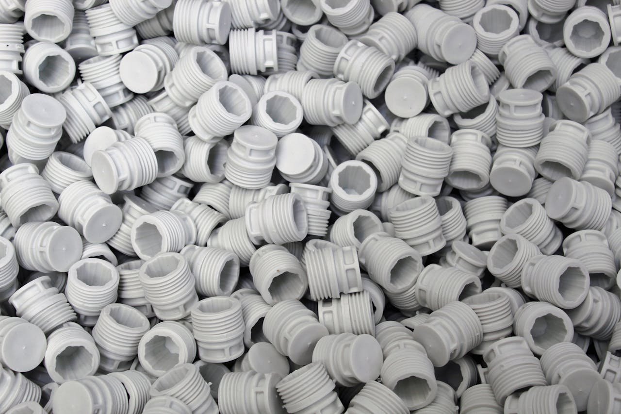 A high-quality image of numerous white plastic screw caps piled together, showcasing industry production.